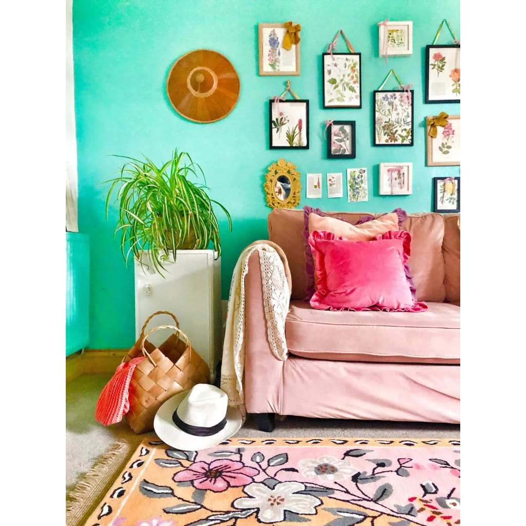 A vibrant living room featuring a pastel paradise hand tufted area rug with floral patterns. The wool rug complements the vintage decor, including a blush sofa with pink cushions, and a gallery wall of botanical prints. Ideal for those seeking stylish living room area rugs that add a touch of elegance and warmth.