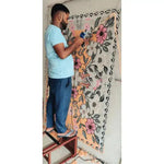 A skilled artisan hand-tufting a vibrant Pastel Paradise area rug with floral patterns, perfect for adding a touch of elegance to living room spaces. This wool rug showcases vintage charm with its intricate design, ideal for those seeking living room area rugs with a floral motif.