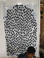 artisan tufting rug next to a large black and white patterned rug against a brick wall.
