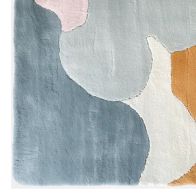 Close-up view of the Pastel Skies Hand Tufted Wool Rug, showcasing its abstract design with soft blue, pink, gray, white, and orange hues. This elegant area rug is perfect for adding a touch of sophistication to any living room, combining comfort and style.