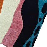 Close-up view of the Pattern Play Hand Tufted Wool Rug Runner showcasing vibrant abstract designs with blue, pink, and black colors. Ideal as a contemporary area rug, this versatile piece adds a stylish touch to kitchens, hallways, offices, or bathrooms. Made from wool, it's perfect for those seeking high-quality large area rugs for living rooms or as kitchen runner rugs.