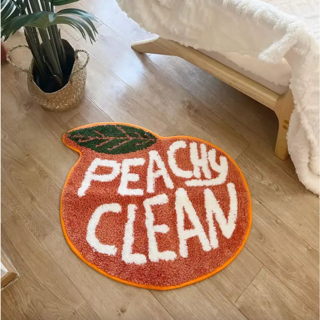 A vibrant Peachy Clean bathmat shaped like a peach, adding a playful touch to any room. This runner rug is perfect for kitchens, hallways, or bathrooms, blending style with functionality. Made from soft cotton, it brings warmth and comfort to your space.