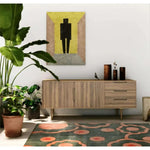 A stylish area rug with a vibrant abstract design featuring peach and green tones, perfect for enhancing a bedroom or dining room. The wool rug adds a cozy touch to the modern decor, complementing the wooden sideboard and indoor plants.