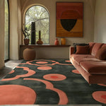 Charcoal rug with peachy floral motifs in a sunlit room with a terracotta sofa