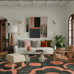 Peachy charcoal floral rug in a styled living room with a white sofa and rattan chair