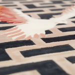 Close-up of a geometric patterned rug with black, beige, and pink colors.