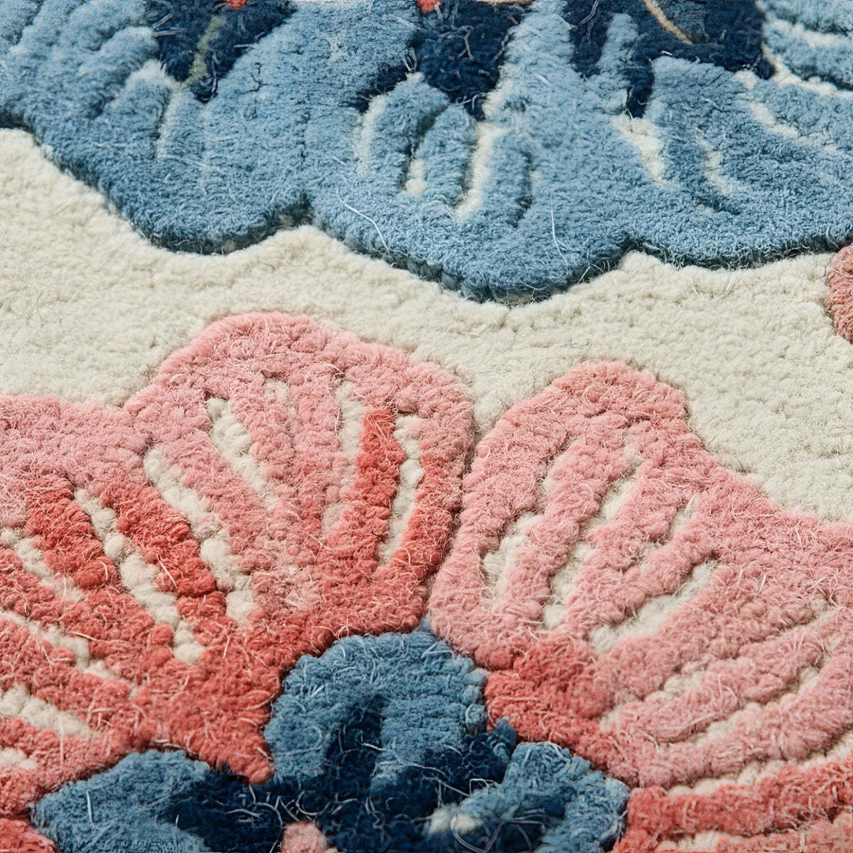 Close-up of a textured rug with floral patterns in blue and pink.