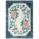 The Petal Crest Bloom Hand Tufted Area Rug features a stunning floral design with large pink flowers and lush green leaves, set against a soft beige background. This elegant wool rug is perfect for adding a touch of nature to your living room area. Its intricate border and detailed pattern make it a standout piece among rugs for living rooms.
