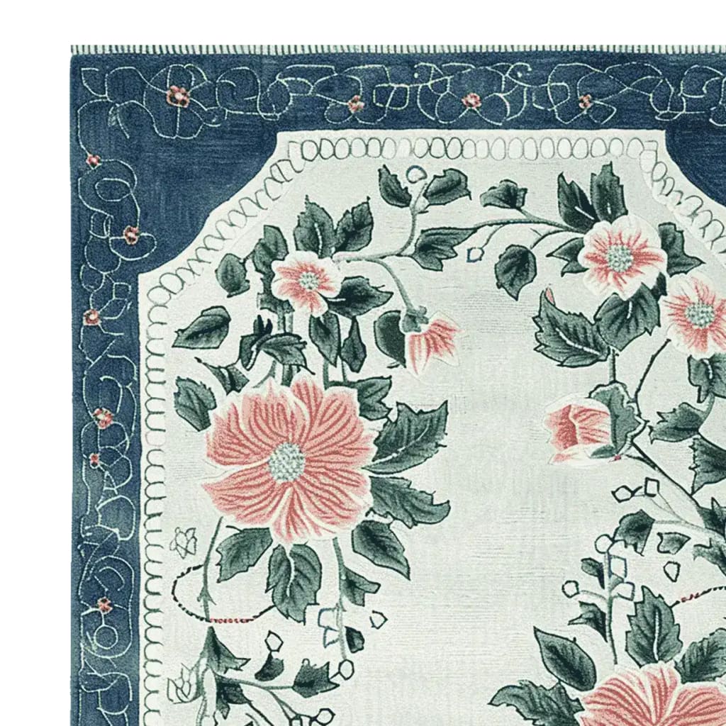 Corner view of the Petal Crest Bloom Hand Tufted Area Rug showcasing its elegant floral pattern. This exquisite wool rug, perfect for living rooms, features lush pink flowers and green leaves on a soft background, framed by an intricate blue border, making it a stunning choice for those seeking a floral rug to enhance their home decor.
