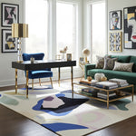 Modern living room with a desk, sofa, and abstract rug.