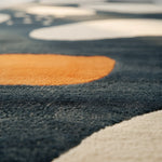 Close-up of a textured rug with orange, black, and beige colors.