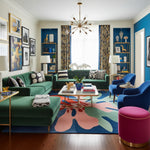 Colorful living room with green sofas, blue chairs, and a patterned rug.