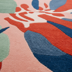 Close-up of a colorful abstract patterned rug with red, blue, and pink colors.