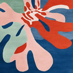 A vibrant hand-tufted area rug featuring an abstract design with bold colors including red, pink, green, and blue. This contemporary square rug is perfect for adding a pop of color to a living room. Made from high-quality wool, it measures 8x10, making it an ideal choice for modern home decor.