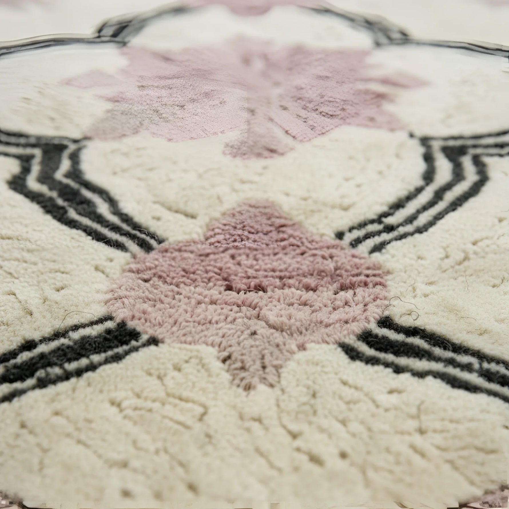 Close-up of a textured rug with pink floral patterns and black geometric lines.