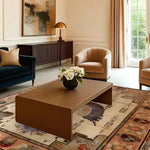 Elegant living room featuring the Pharaoh's Feathers Hand Knotted Area Rug with a vintage design. This 8x10 Persian rug complements the modern furniture, including a brown coffee table, a dark blue sofa, and beige armchairs. The rug's intricate patterns add a touch of sophistication to the space, perfect for those seeking stylish rugs for living rooms.