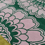 Close-up view of a hand-tufted wool area rug featuring a pink gingko leaf pattern on a green background. Ideal for large living rooms, this stylish 8x10 wool rug adds a touch of elegance to any living space.