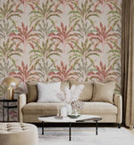 Pink-green banana grove wallpaper behind a beige velvet sofa with marble coffee table in a lounge