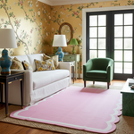 Living room with floral wallpaper, white sofa, green armchair, and Pink Handwoven Reversible Cotton Scalloped Rug.