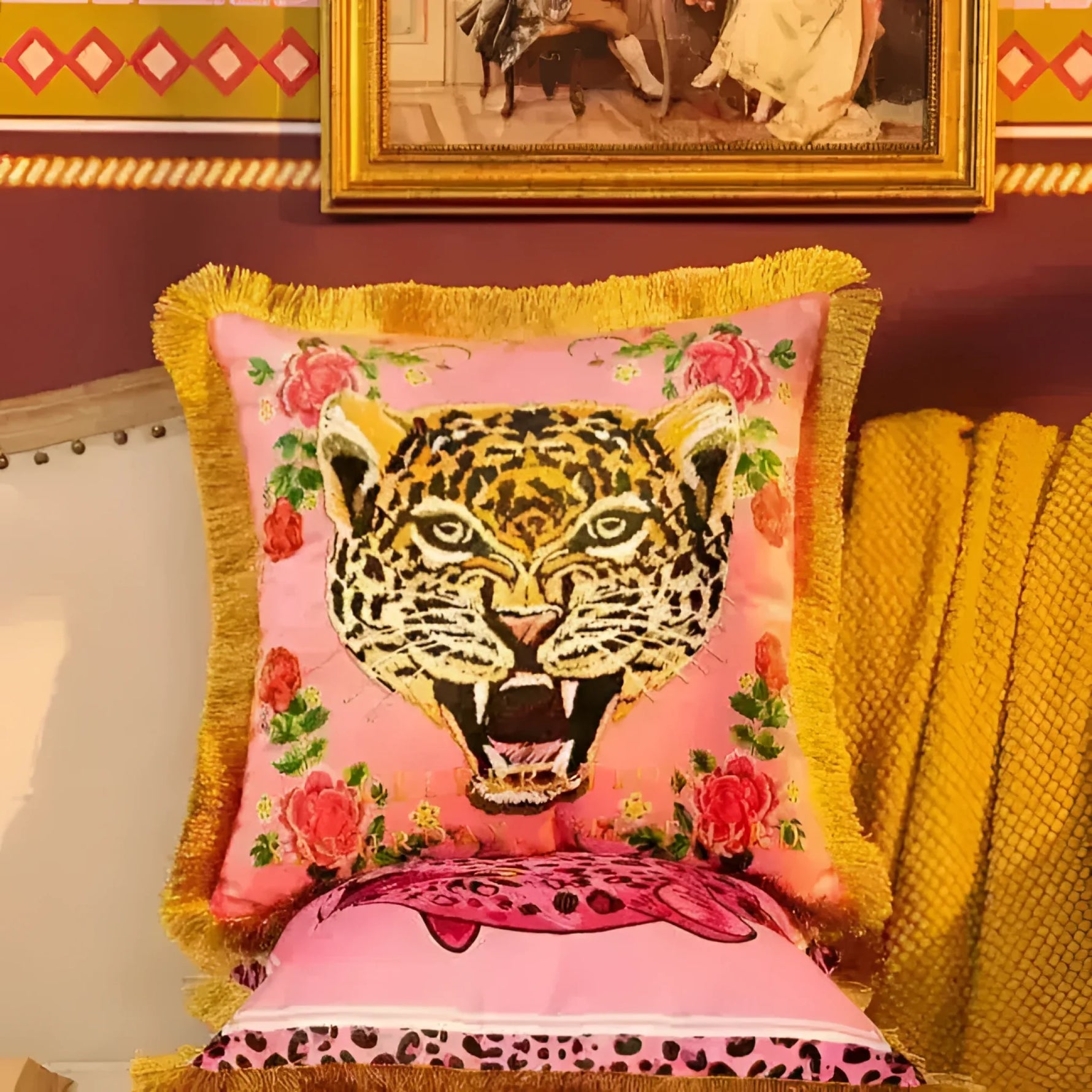 Vibrant pink throw pillow featuring a fierce leopard face design surrounded by floral accents, complemented by a luxurious gold fringe.