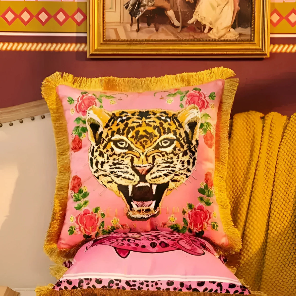 Vibrant pink throw pillow featuring a striking leopard face design with floral accents and gold fringe, perfect for adding a bold touch to your home decor.