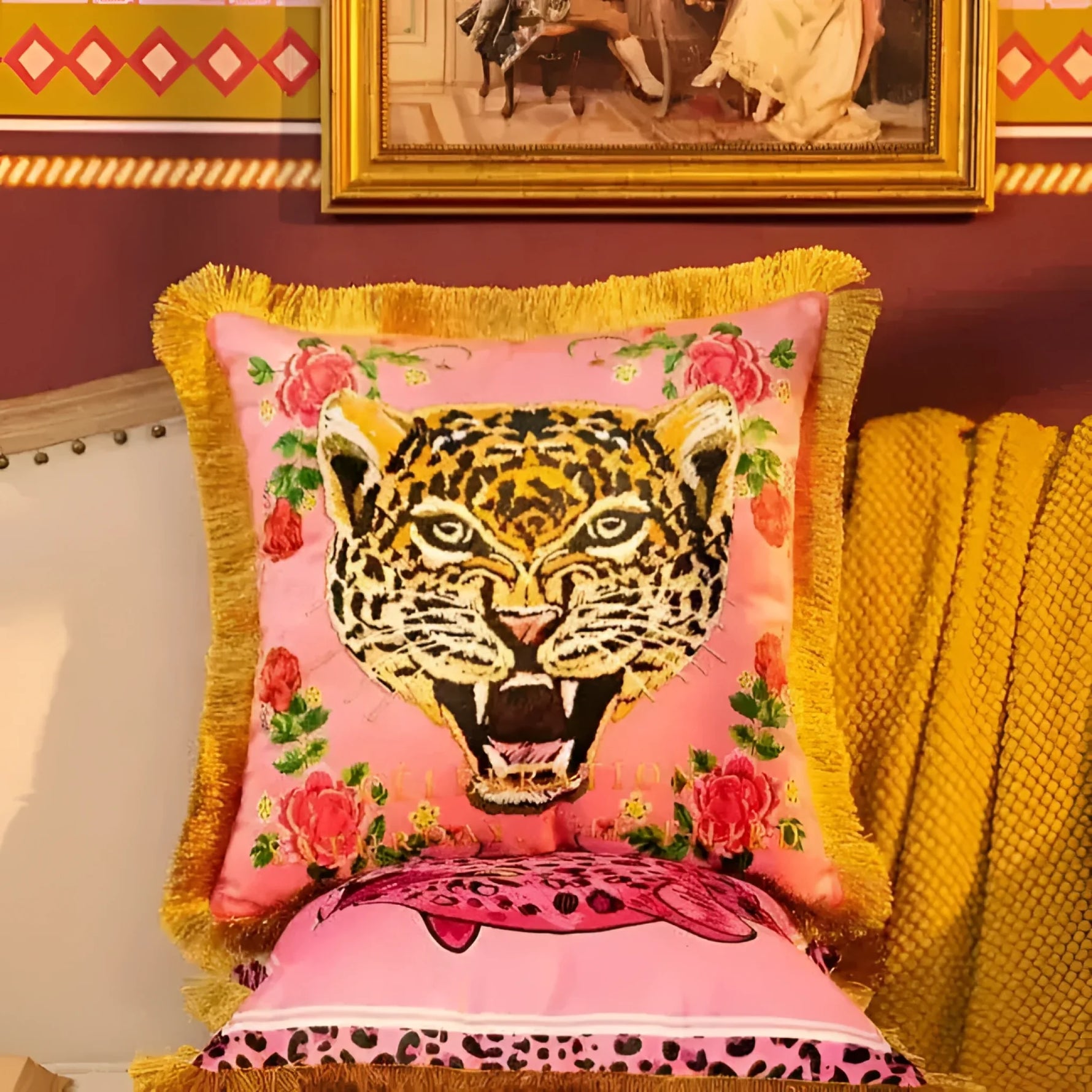 Vibrant pink throw pillow featuring a striking leopard face design with floral accents and gold fringe, perfect for adding a bold touch to your home decor.