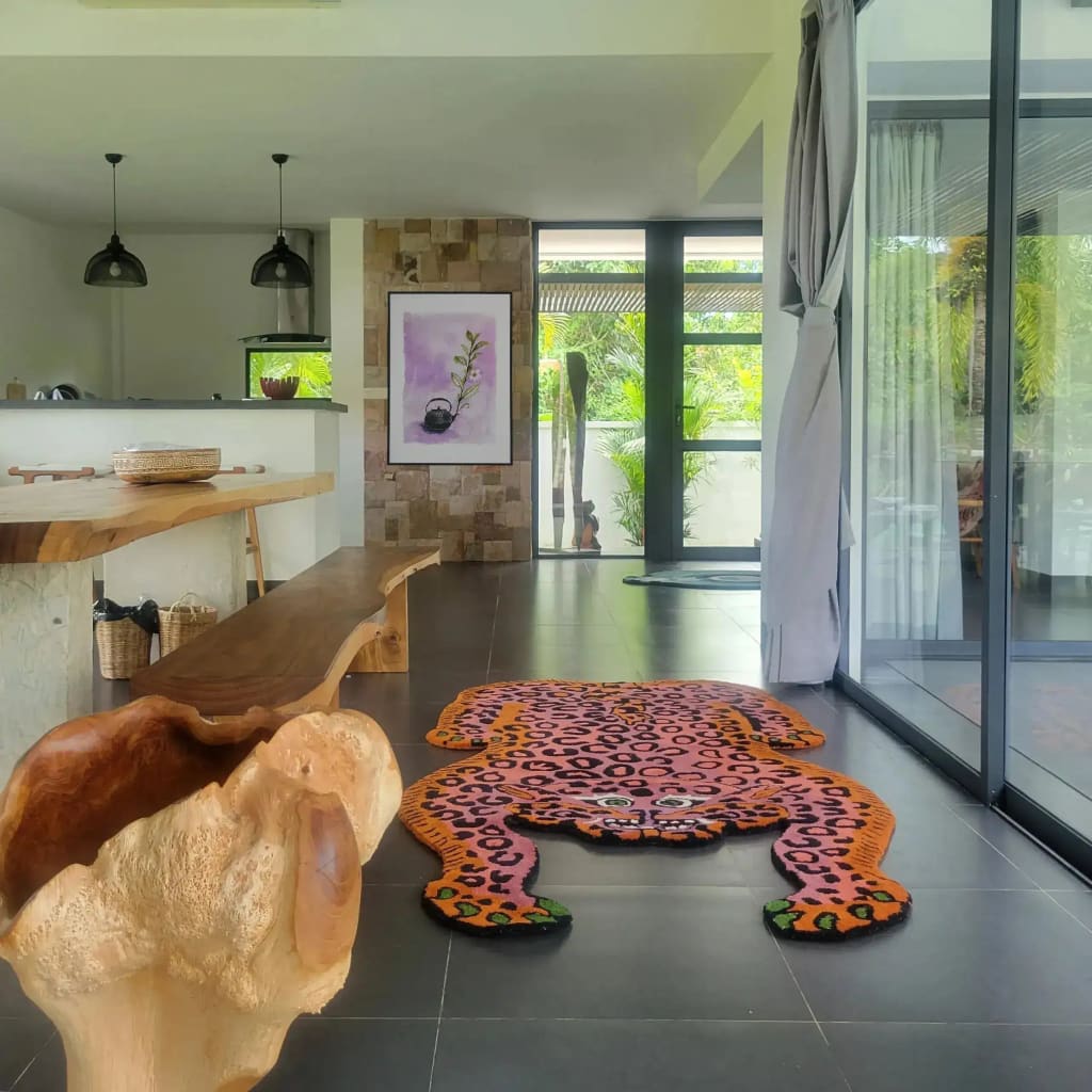 A stylish living room featuring a unique Pink Leopard Yogi Accent Wool Rug placed on a sleek tile floor. This large area rug, ideal for living rooms, showcases a vibrant vintage design with bold pink and orange hues. The rug's playful leopard pattern adds an artistic touch to the modern decor, making it a standout piece among wool rugs for living room settings.