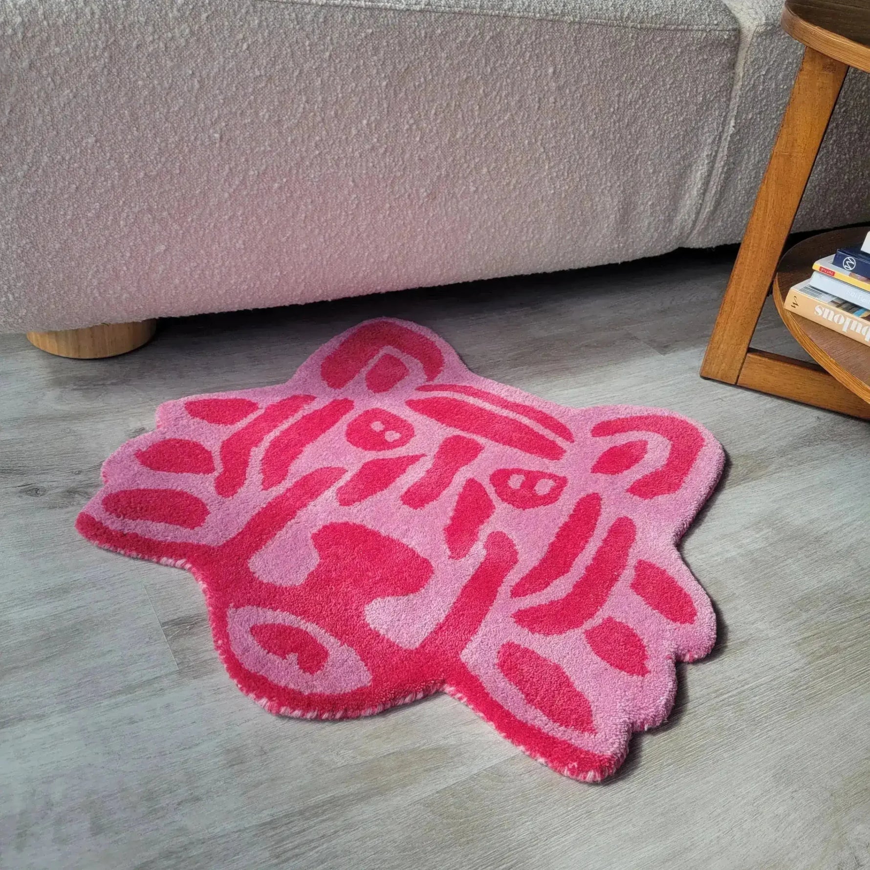 A vibrant pink lion face hand-tufted rug, perfect for adding a playful touch to an office space. This round wool area rug features bold abstract patterns in varying shades of pink, making it a stylish choice for office rugs. Positioned on a light wooden floor, it adds a pop of color and creativity to any office setting.