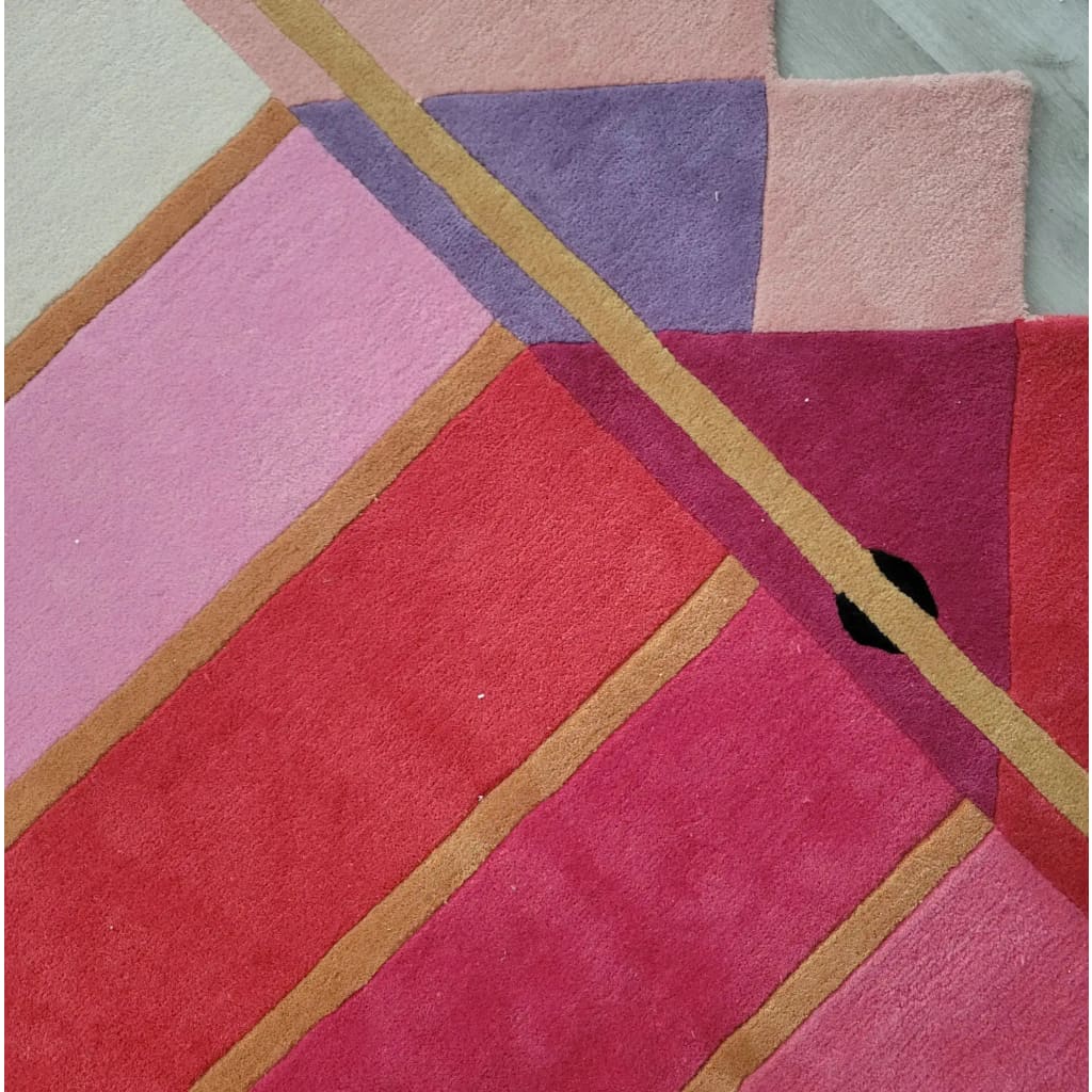 Close-up view of the Pink Prism Geometric Hand-Tufted Wool Rug showcasing its vibrant geometric pattern with shades of pink, purple, and red. Ideal for adding a contemporary touch to living room area rugs, this wool rug combines modern design with vintage charm, perfect for enhancing any living room decor.