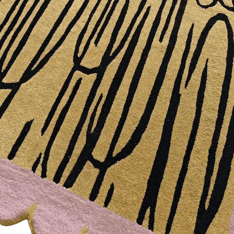 Close-up view of a contemporary area rug featuring a pink scalloped edge with an abstract black pattern on a golden wool background. Perfect for adding an artistic touch to your living room, this hand-tufted wool rug measures 8x10, making it an ideal choice for area rugs in living rooms.