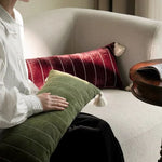 Plush velvet throw pillow cover with tassels, featuring a green color and textured stripes, placed on a cozy sofa.