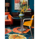 A vibrant dining room featuring a Poppy Symphony Hand Tufted Area Rug with bold floral patterns in orange and yellow, perfectly complementing the modern decor. The colorful wool rug enhances the formal dining room atmosphere with its artistic flair.
