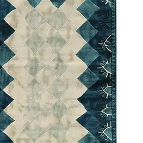 A contemporary wool area rug featuring an abstract geometric pattern with a blend of soft beige and deep teal tones. Perfect for adding a modern touch to living rooms or offices, this hand-tufted rug showcases intricate detailing and a unique design that complements various decor styles.