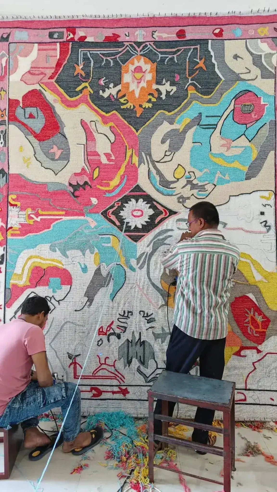 Artisans crafting a Prismatic Core Hand Tufted Rug in vibrant colors, ideal for large living room spaces. This wool rug features a vintage abstract design, perfect as a statement piece in any living room area.