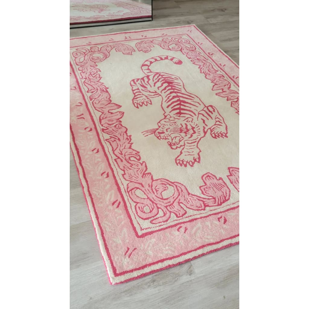 A stylish area rug featuring an abstract pink tiger design against a soft beige background, perfect for a large living room. This hand-tufted wool rug adds a touch of elegance and artistic flair to any living space.