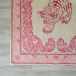 Close-up view of the Prowess in Pink Garden Hand-Tufted Area Rug, featuring an intricate pink tiger design with decorative border, perfect for adding elegance to a large living room. Made from high-quality wool, this rug enhances any space with its luxurious texture and vibrant colors.