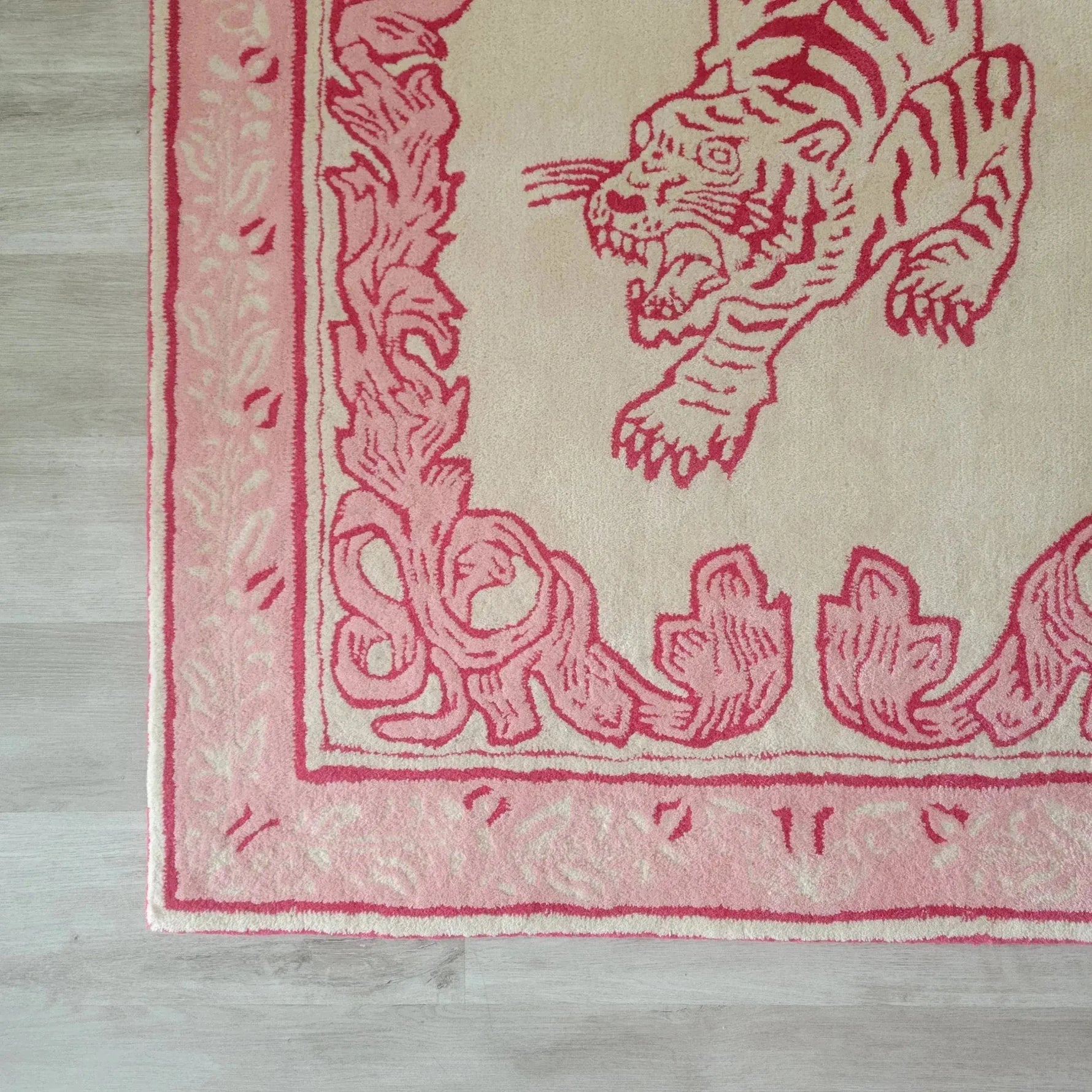 Close-up view of the Prowess in Pink Garden Hand-Tufted Area Rug, featuring an intricate pink tiger design with decorative border, perfect for adding elegance to a large living room. Made from high-quality wool, this rug enhances any space with its luxurious texture and vibrant colors.