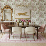 Dining room with floral wallpaper, a leopard painting, and a wooden table with chairs.