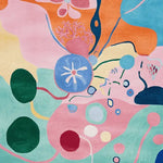 Vibrant and colorful area rug with an abstract design, featuring floral and organic shapes in shades of pink, blue, orange, and green. This contemporary wool rug adds a lively touch to large living room spaces.