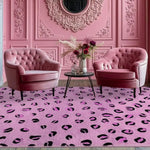 A cozy dining room setup featuring a vibrant Purple Leopard Spots Hand Tufted Wool Rug. The large area rug anchors the space with its bold design, complemented by elegant pink armchairs and an ornate pink wall. Ideal as a dining table rug or in a formal dining room, this wool rug adds a touch of modern luxury.