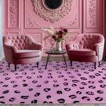 A cozy dining room setup featuring a vibrant Purple Leopard Spots Hand Tufted Wool Rug. The large area rug anchors the space with its bold design, complemented by elegant pink armchairs and an ornate pink wall. Ideal as a dining table rug or in a formal dining room, this wool rug adds a touch of modern luxury.