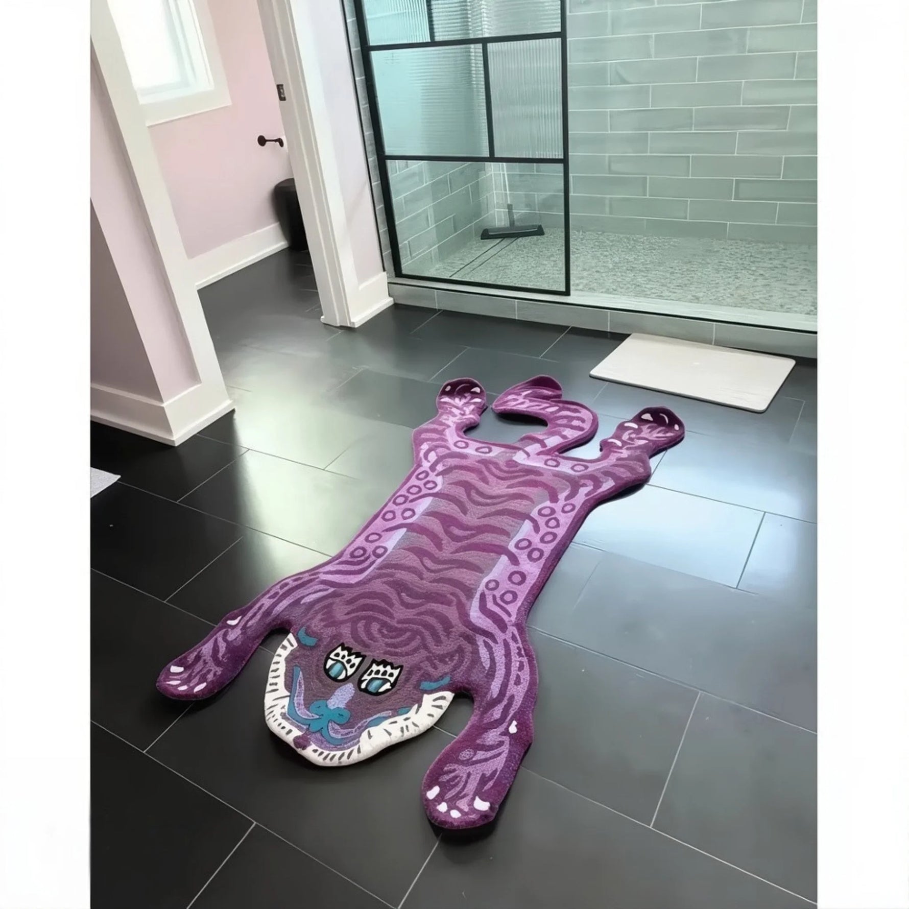 Purple Tibetan tiger-shaped wool rug placed on dark bathroom tiles.