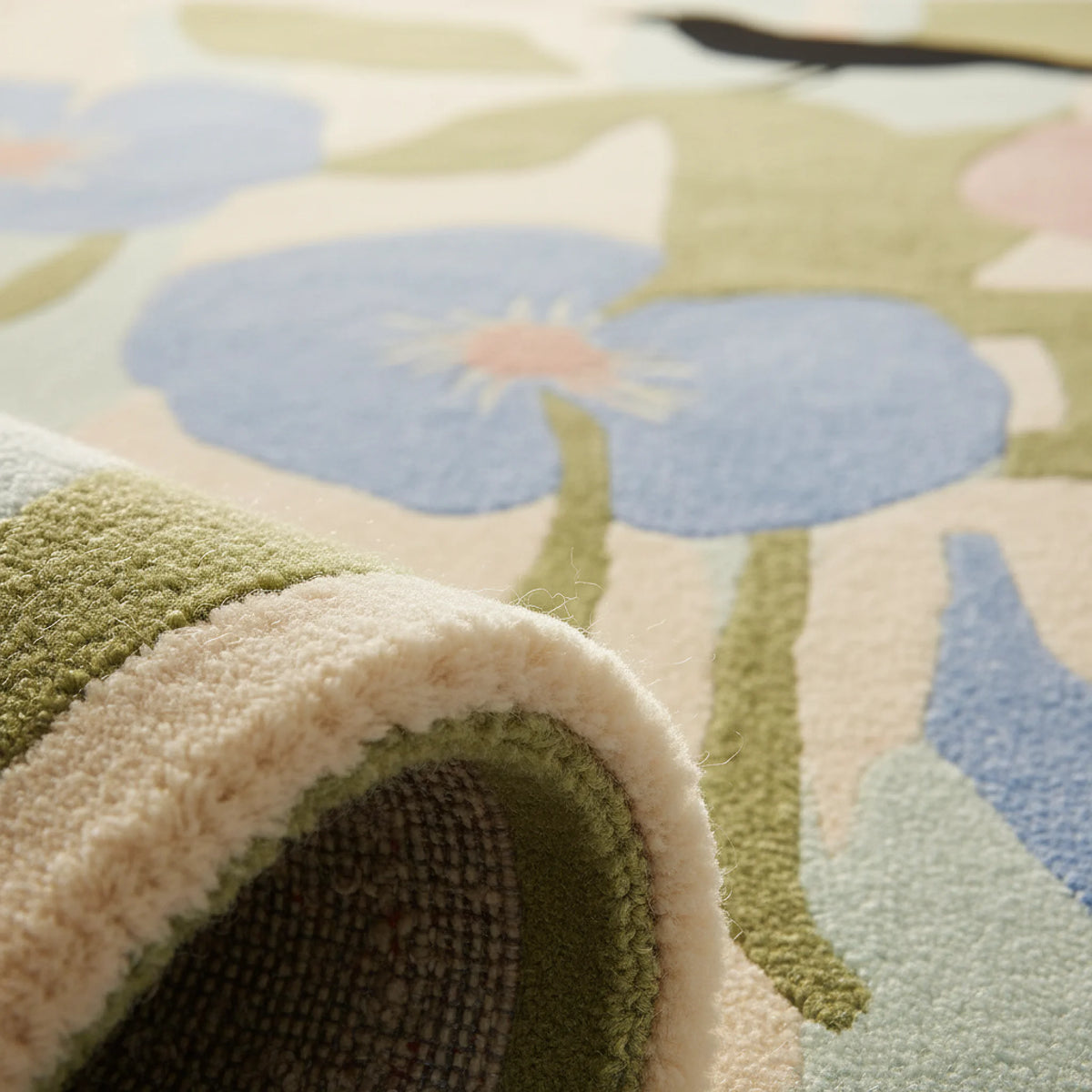 Close-up of a floral-patterned rug with green, blue, and beige colors.