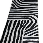 Top view of a Radiant Burst Hand Tufted Wool Rug featuring an abstract black and white pattern, ideal as a runner rug for kitchens, hallways, or bathrooms. This contemporary wool rug adds a modern touch to any space.