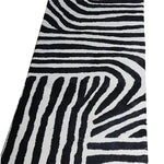 Top view of a Radiant Burst Hand Tufted Wool Rug featuring an abstract black and white pattern, ideal as a runner rug for kitchens, hallways, or bathrooms. This contemporary wool rug adds a modern touch to any space.