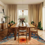 A beautifully decorated living room featuring a large area rug with a vibrant floral design. This wool rug adds a touch of elegance and warmth to the space, complementing the wooden dining table and chairs. Perfect for anyone looking to enhance their living room with stylish area rugs.
