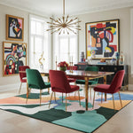 Dining room with colorful chairs and abstract art on a patterned rug.
