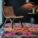 Vibrant Radiant Spectrum Wool Hand Knotted Square Area Rug in a cozy living room setting. The colorful abstract design complements the woven chair and elegant side table with flowers, creating a warm and inviting atmosphere.