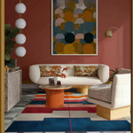 A cozy dining room featuring a vibrant Radiant Sunscape Hand Tufted Wool Rug. The contemporary area rug showcases bold geometric patterns in red, blue, and white, perfectly complementing the modern decor. Ideal for adding warmth and style to any bedroom or dining room.