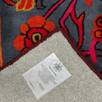 Close-up of the Red Bloom Harmony Rug, a hand-tufted wool area rug, showcasing vibrant floral patterns in orange and red on a dark background. Perfect for adding a vintage touch to dining rooms and living rooms. Ideal as an 8x10 living room rug or dining room area rug.